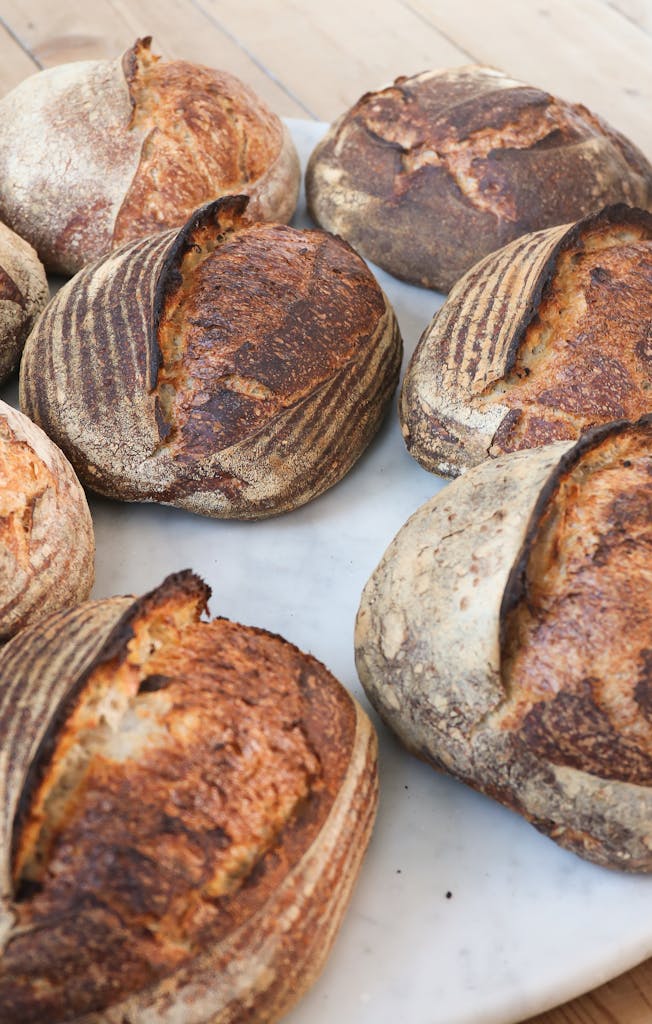sourdough beginner struggles - Freshly baked artisan sourdough bread loaves displayed on a marble surface.